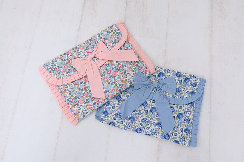Two floral-patterned Liberty Print pouch bags with bows on a light background